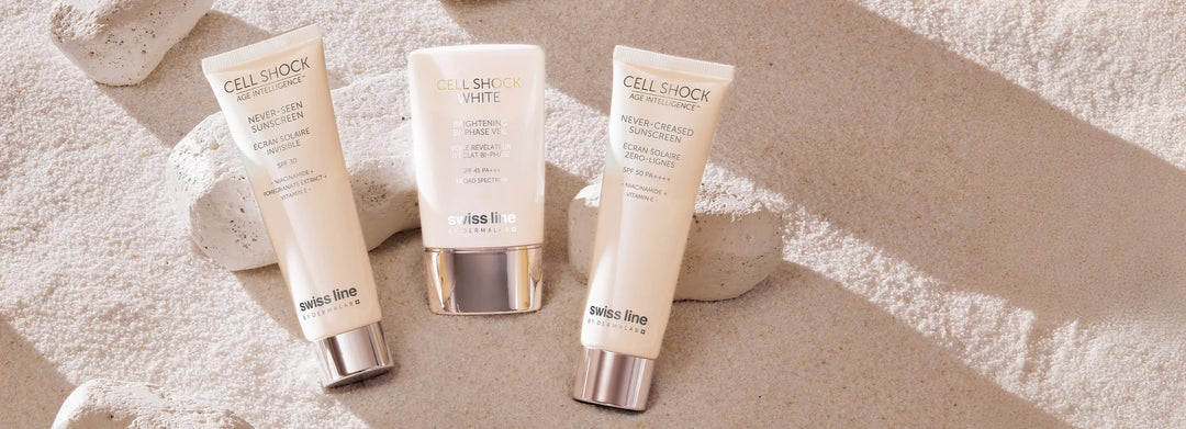 Three Swissline Sunscreens against white sand and rock background
