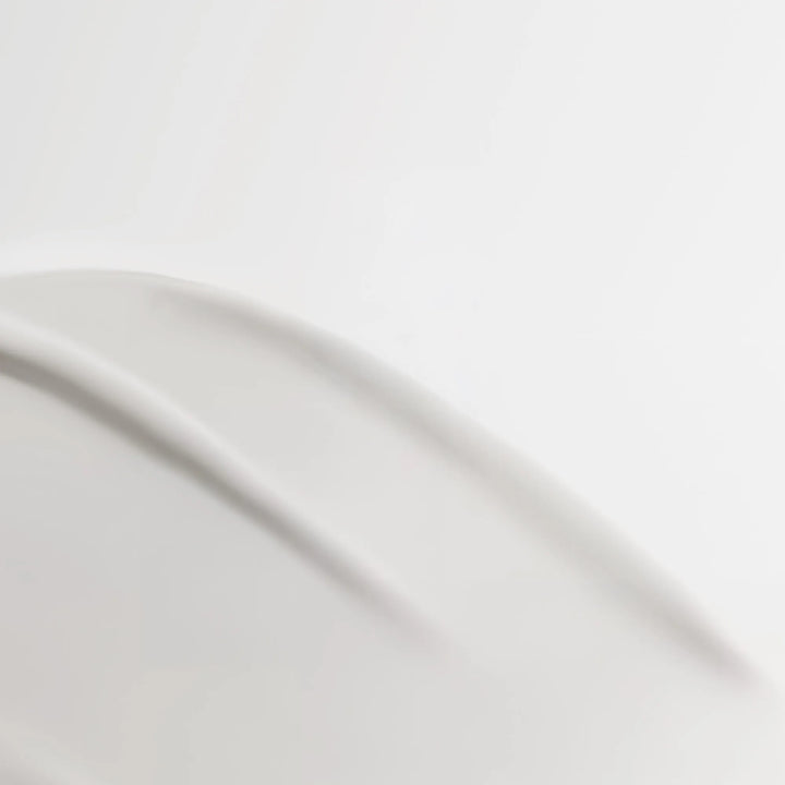 Close-up of a curved white milky texture with soft shadows on a light gray background