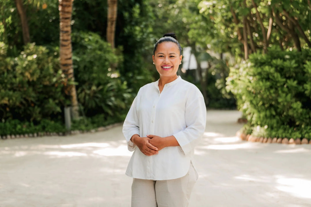 Person wearing a white outfit standing in a garden with greenery