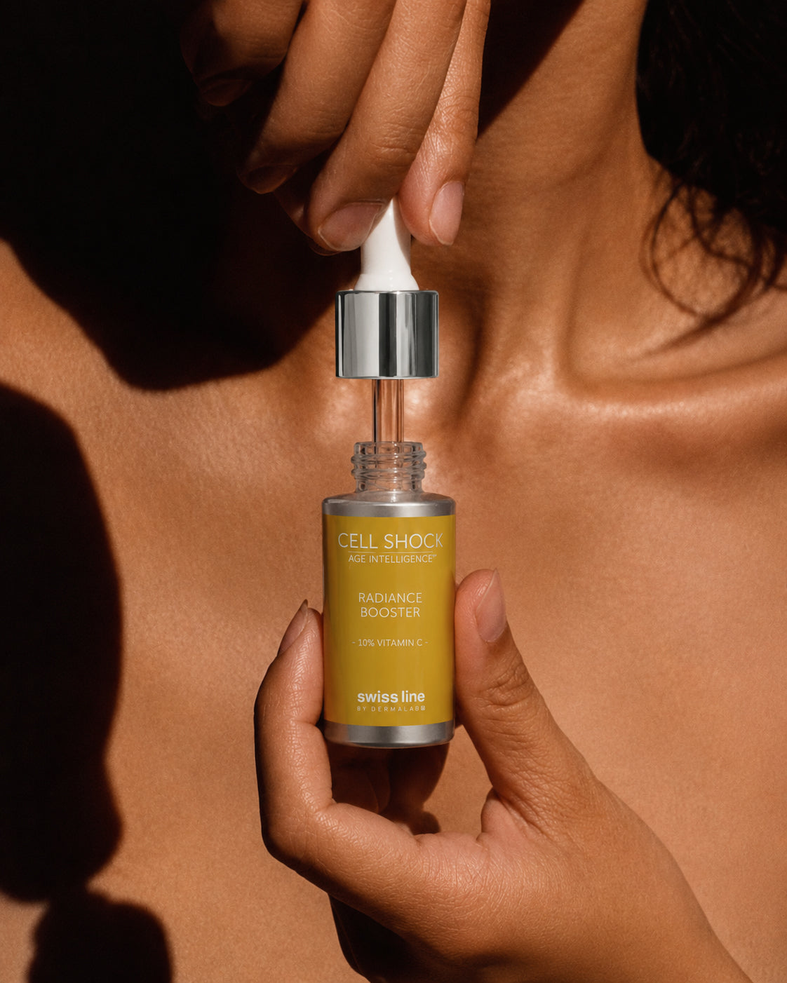 Hand holding a skincare serum bottle labeled 'Cell Shock' against a brown background