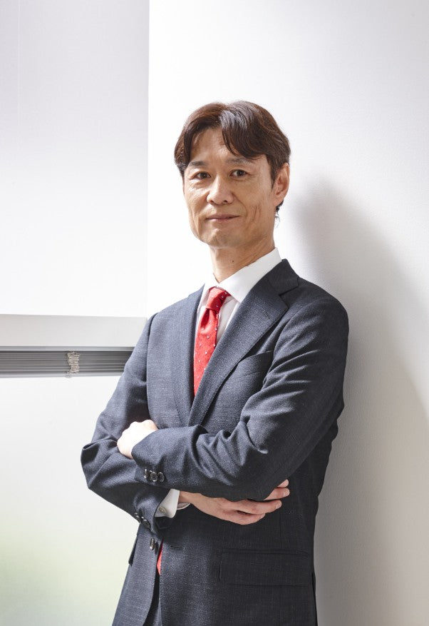 Man in a suit with arms crossed against a white wall